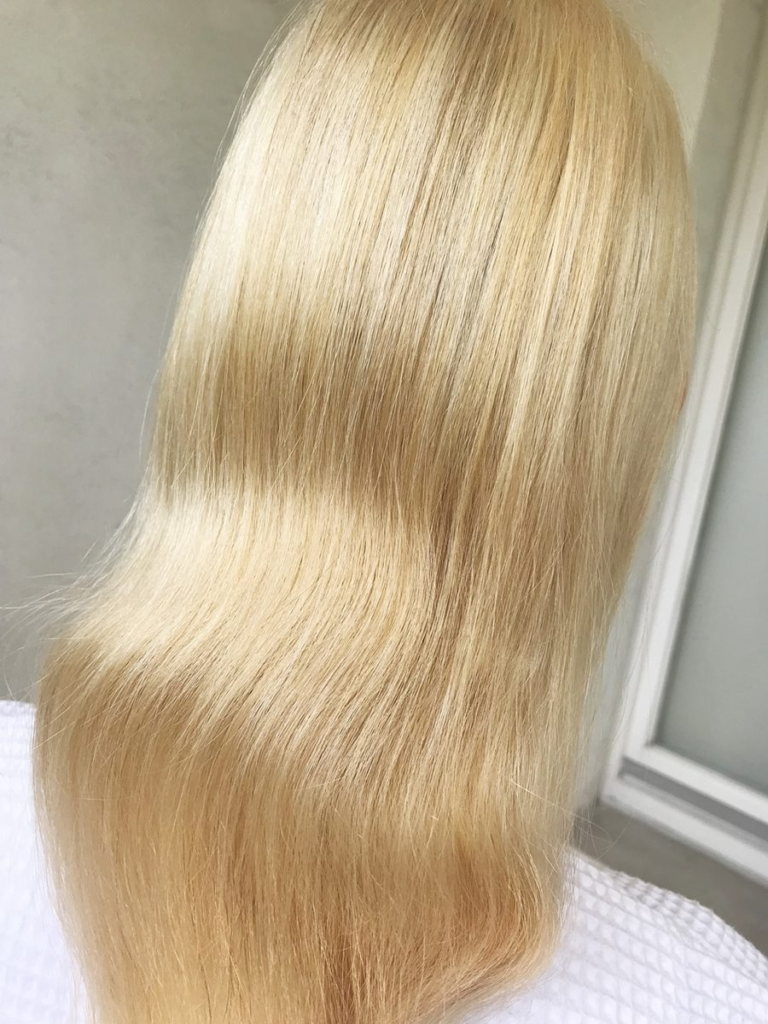 alt="Friseurin trägt Blondierwäsche im Salon auf"